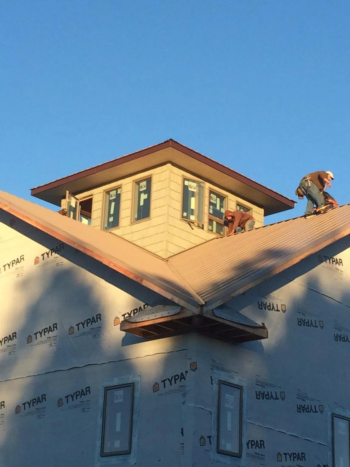 Roofers working around a rooftop cupola on a new metal roof at sunset — Roof Waterproofing in Martinsburg by Roofing Brothers
